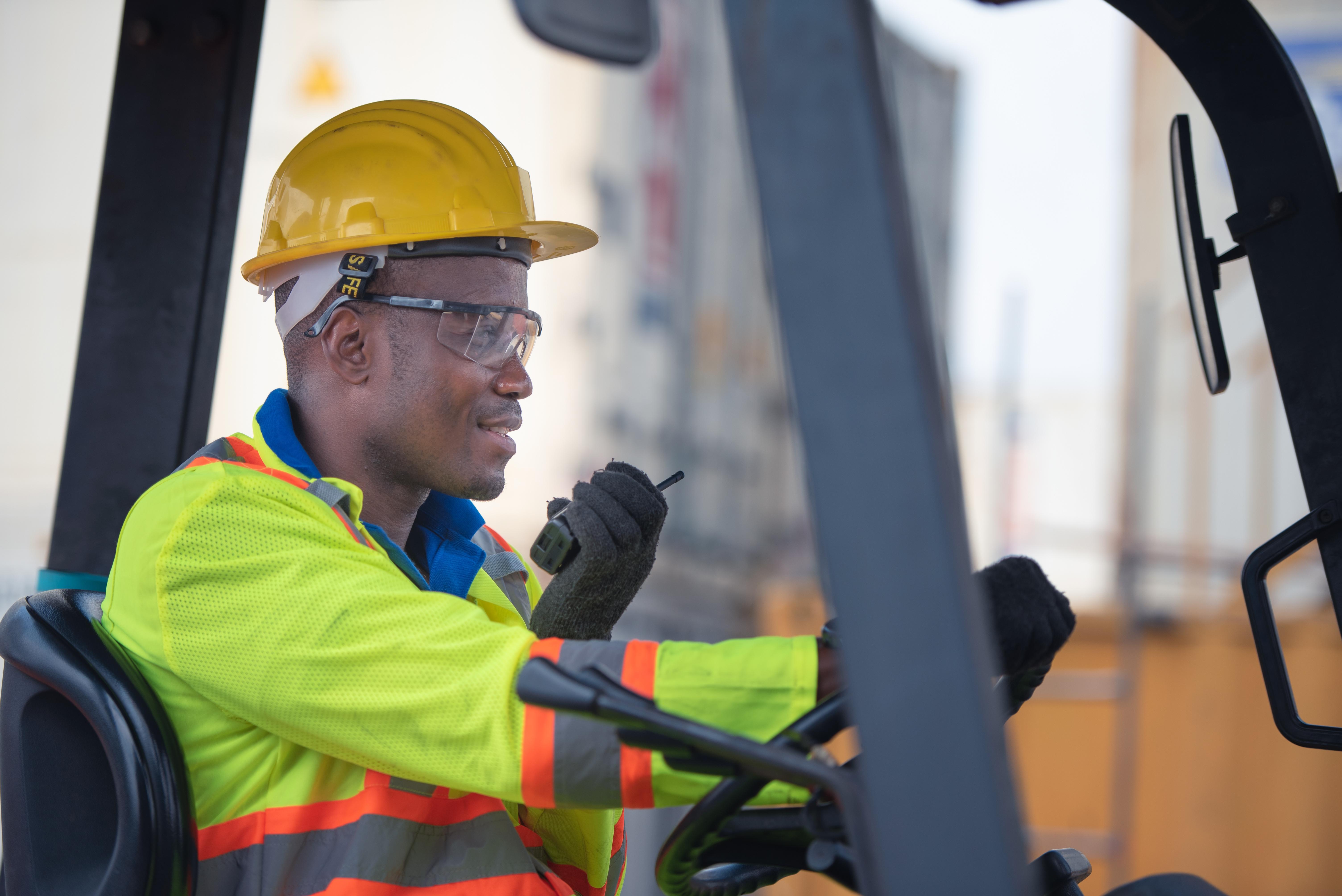 Forklift operator communicating on a walkie-talkie at an outdoor job site