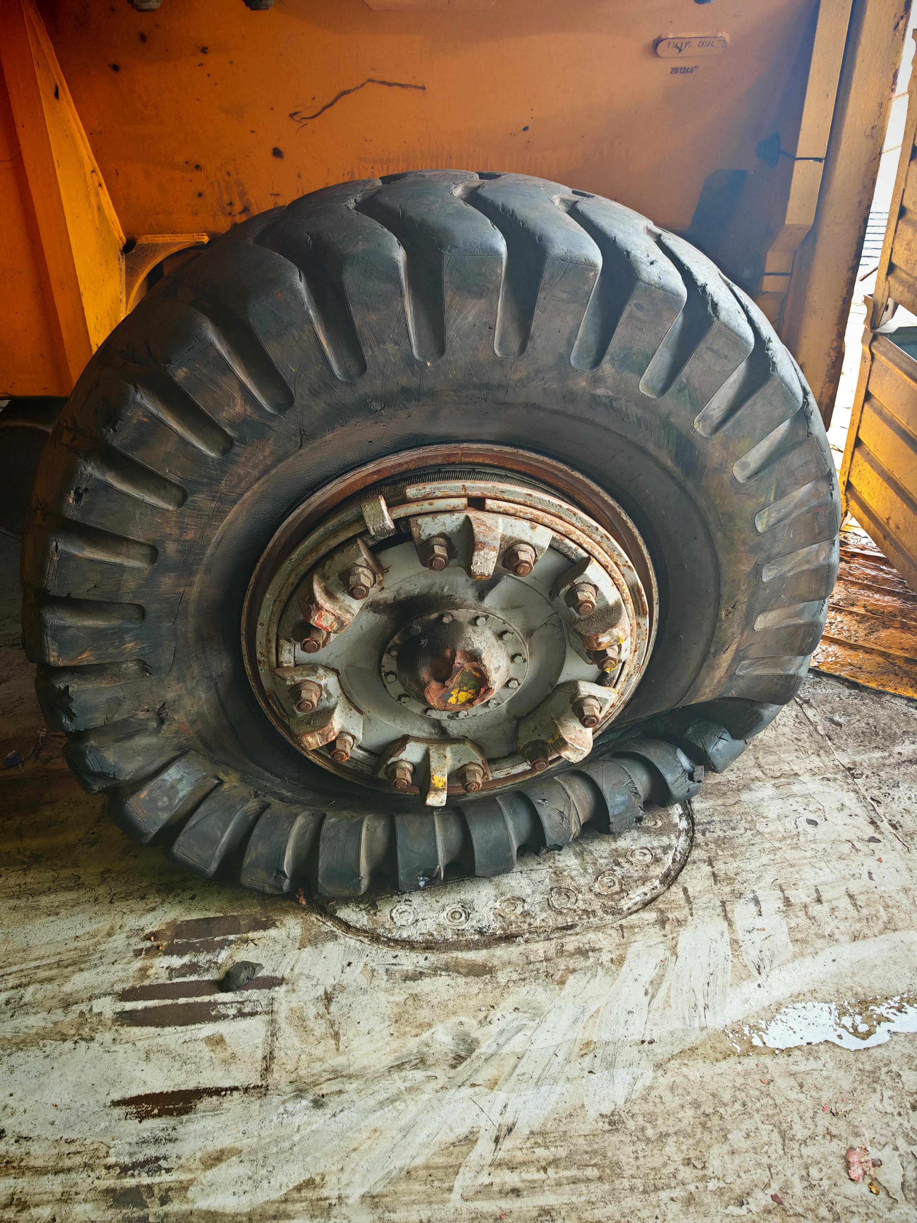 Flat pneumatic tire on a container handler showing severe underinflation and sidewall damage