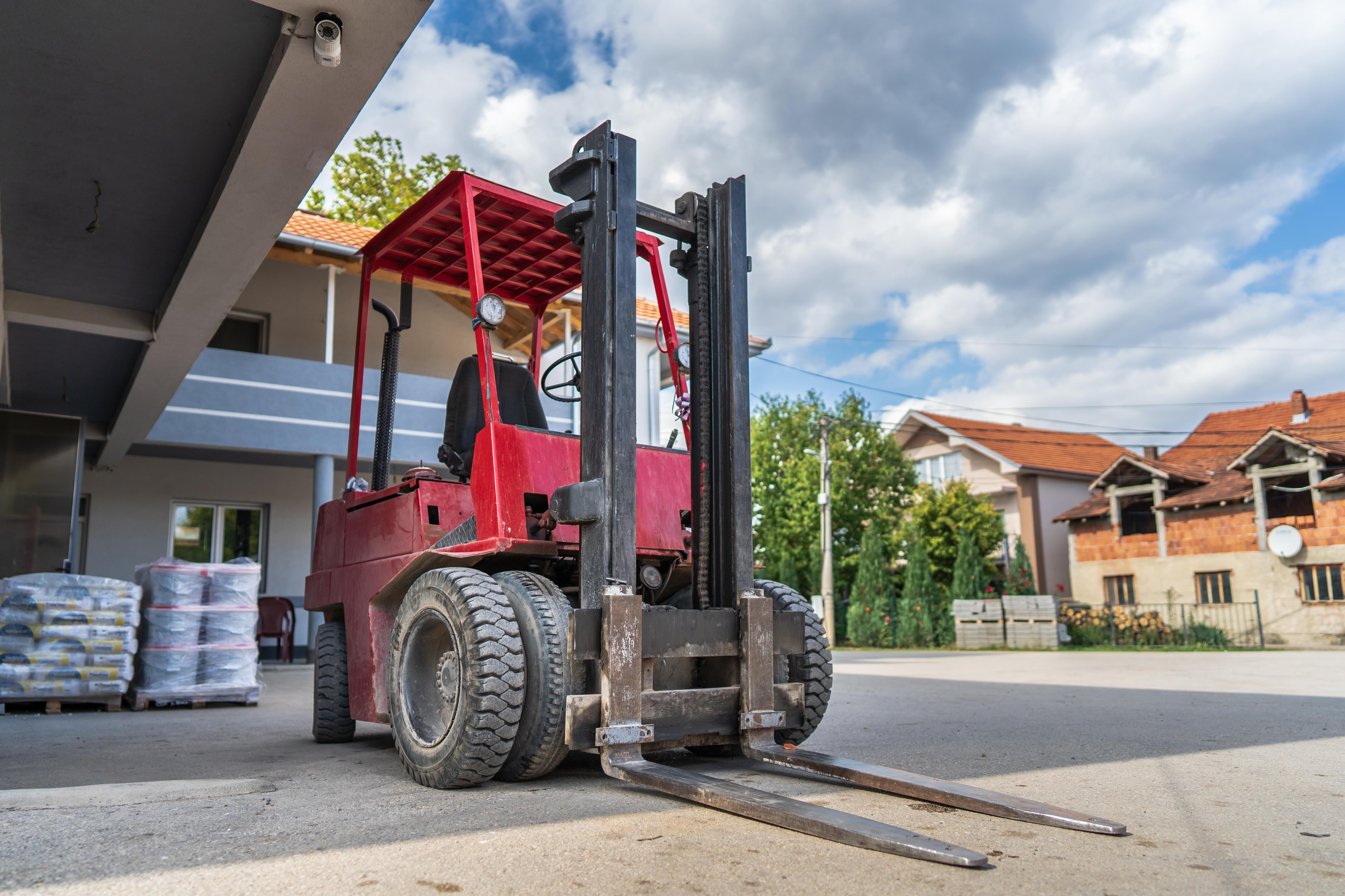 Red counterbalanced forklift with rear steer wheels turned sharply, demonstrating how forklift rear-steer axle pivots for tight turning