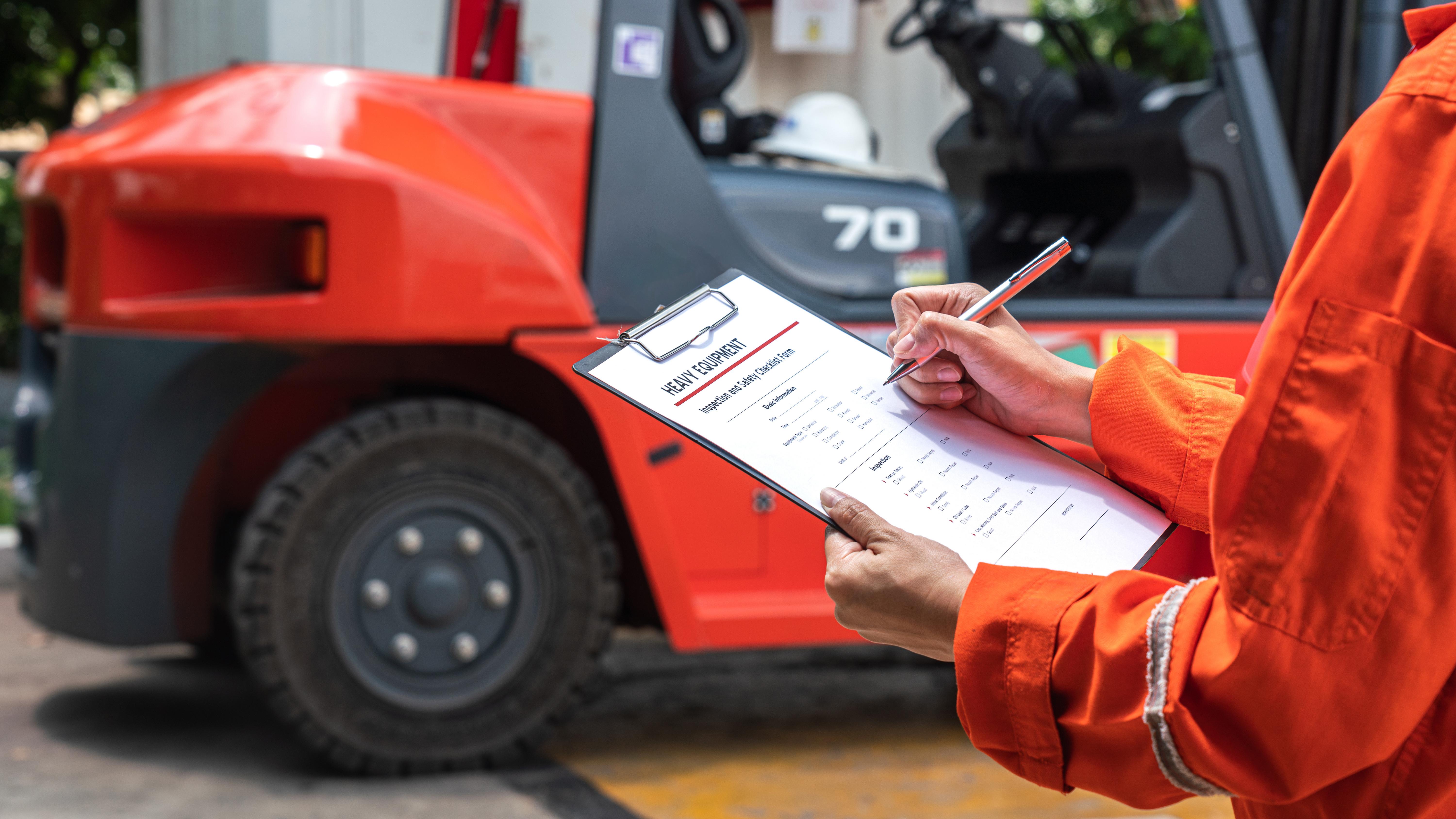 Forklift operator reviewing an equipment inspection checklist Forklift operator reviewing a heavy equipment inspection checklist before tire replacement
