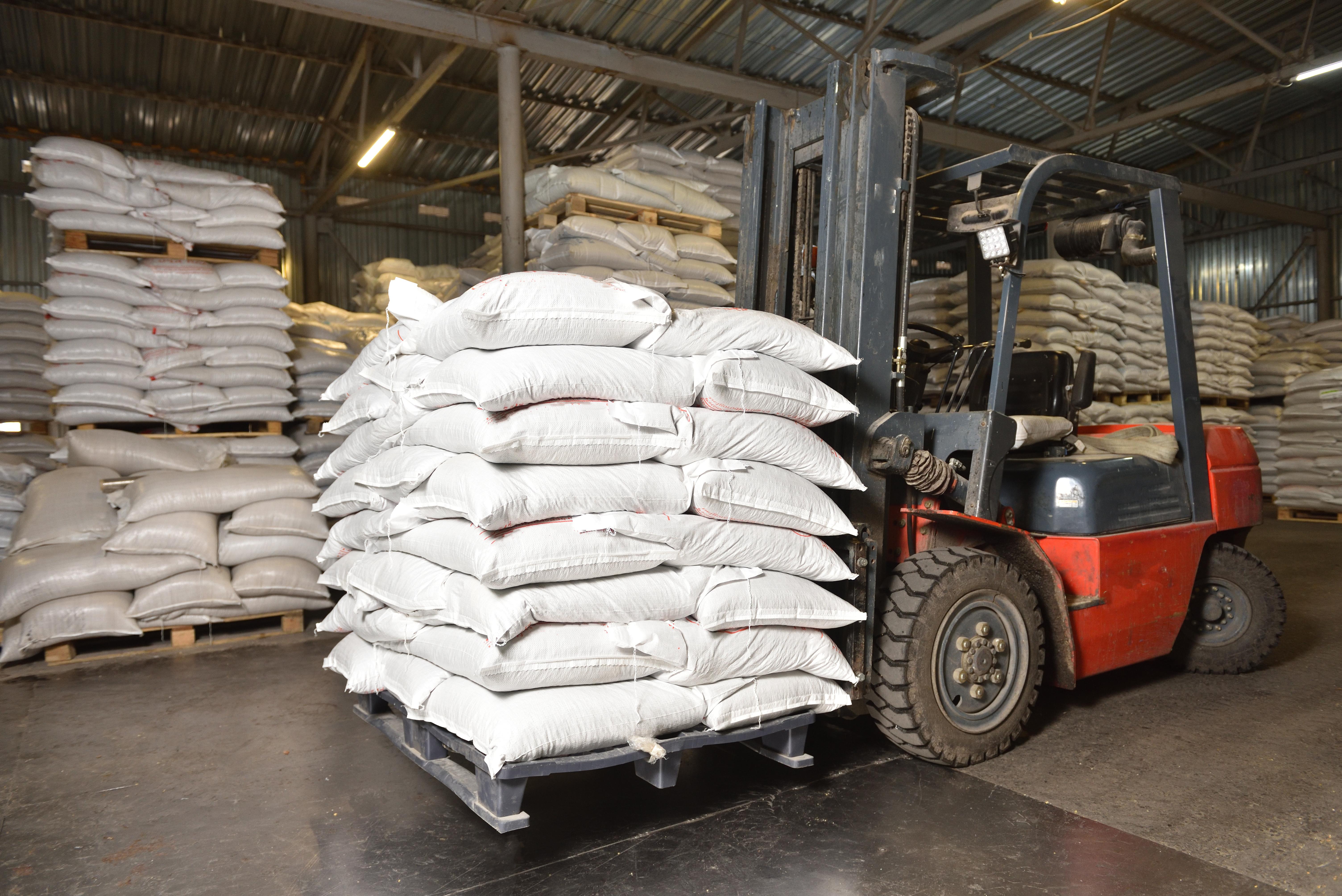 Forklift carrying heavy pallet load in warehouse with rear steer tire visibly turned, showing lateral stress on steer-position tires during loaded operation