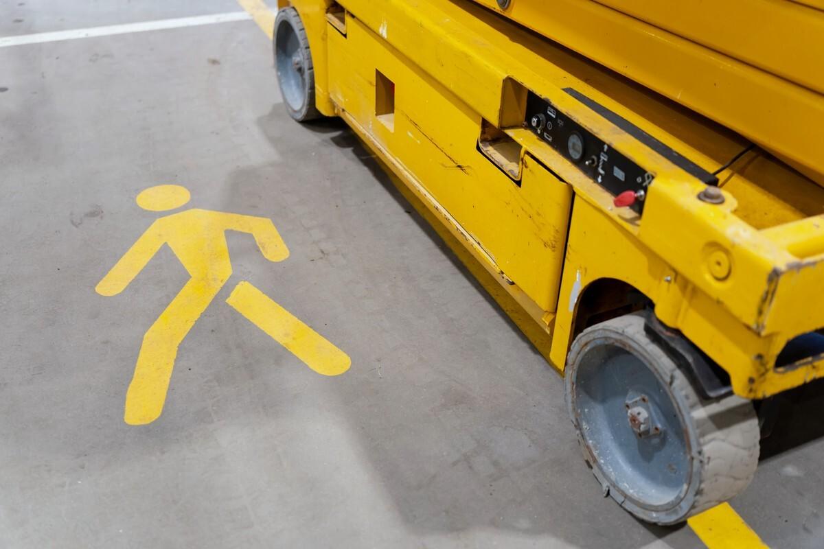 Mold-on solid non-marking tire cured to its steel wheel on a slab scissor lift, beside a painted pedestrian walkway