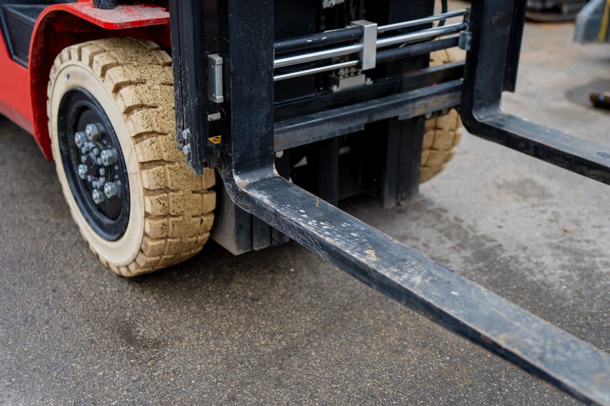 Beige non-marking drive tire on the front axle of a red counterbalance forklift