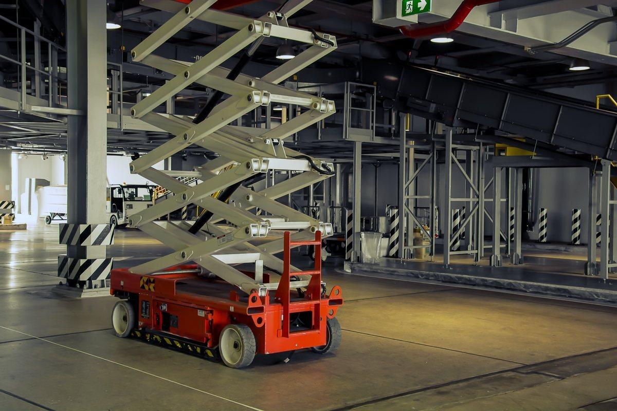 Slab scissor lift on a sealed warehouse floor wearing a mix of light gray non-marking and black solid tires