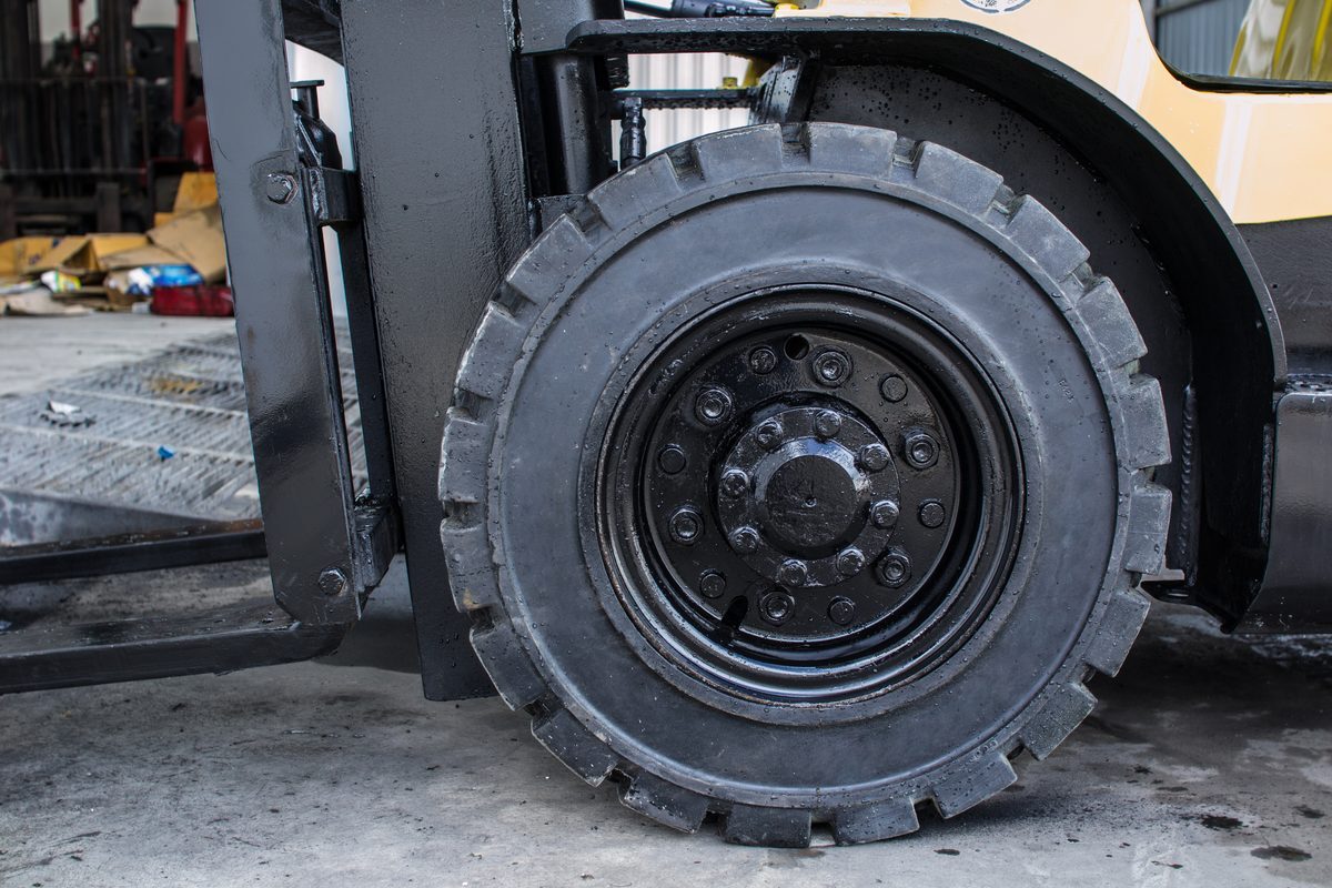 Close-up of a solid pneumatic lug-tread drive tire on the front axle of a forklift